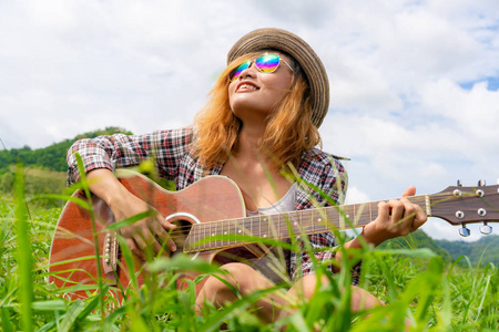 快乐的女人弹吉他与自然背景。 音乐和放松的概念。