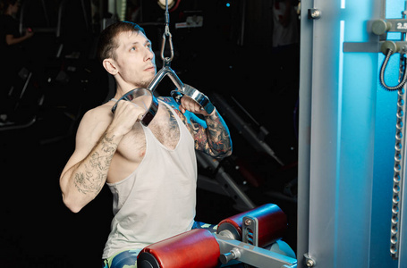 英俊的运动男子在健身房的健身房机器上锻炼