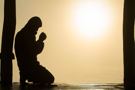 年轻的人类手在日出时向上帝祈祷的剪影,基督教的概念背景.照片