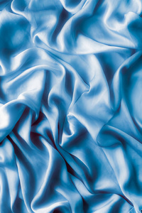 蓝色柔软的丝波，平坦的，优雅的织物纹理，抽象的背景和现代粉彩的概念。 感受奢华的触感