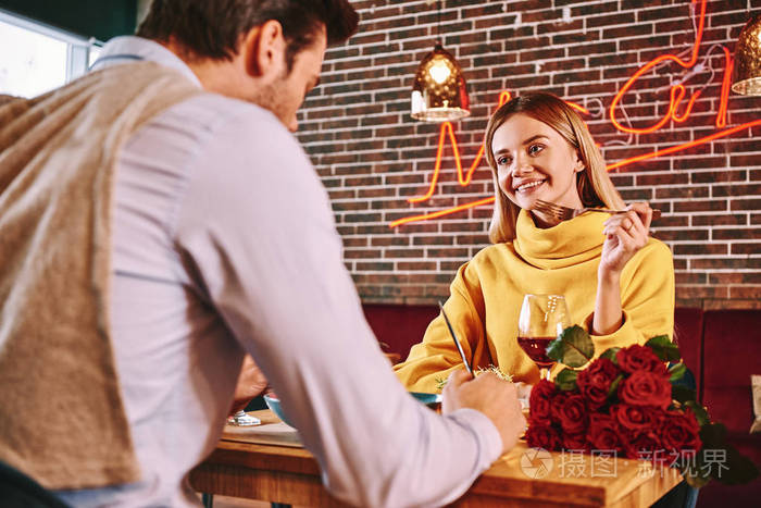浪漫的约会金发碧眼的女人一边看着男朋友一边在餐馆吃饭