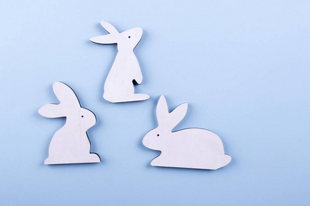 三只白色木制兔子在蓝色粉彩背景上的俯视图.复制空间照片