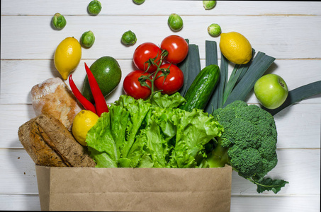 白色木制背景上不同保健食品的纸袋。顶部视图