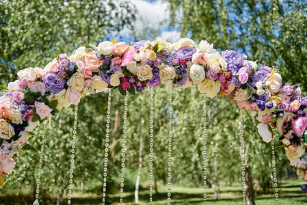 美丽的婚礼拱门装饰白色，粉红色和紫色的花和水晶在花园户外，复制空间。婚礼安排。仪式地点。花卉组成