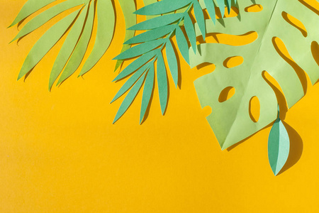 绿色的热带叶子在黄色背景下从纸上剪下来。 夏季概念