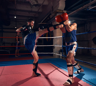 英俊的男拳击手与拳击手在拳击场的搭档进行拳击训练