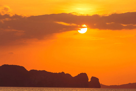 美丽的橙色日落和云彩在岛上的背景。 自然背景