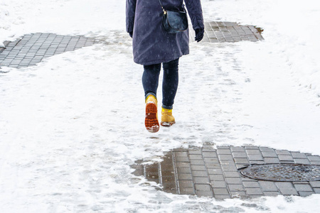 冬天穿黄色皮靴走路. 在一个女人的脚上,沿着冰冷的雪路面行走.