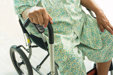 老年妇女手持拐杖，坐在轮椅上
