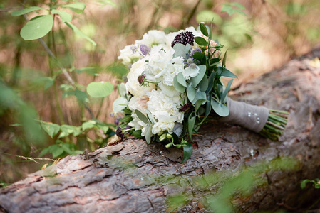 白色牡丹玫瑰和绿色植物的小新娘花束的特写，室外木质背景上的缎带，复制空间。婚礼理念