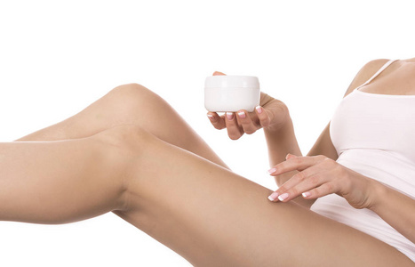 妇女在她的腿上涂奶油在白色背景。皮肤护理和健康概念
