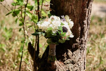 关闭小新娘花束白色牡丹玫瑰和绿色植物与缎带在木材背景户外复制空间。 婚礼概念