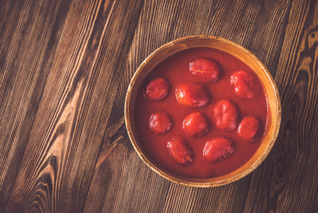 木制背景上的一碗罐装番茄