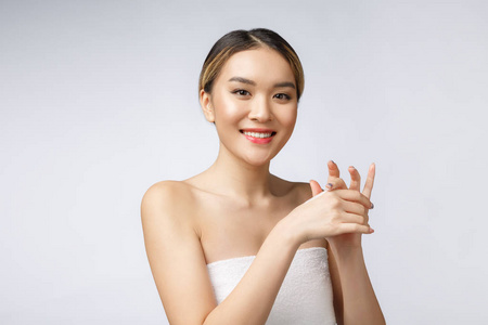 亚洲妇女在皮肤应用化妆品奶油在查出的白色背景