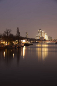 明亮的建筑物反射平静的水，惊人的城市景观与运河夜间阿姆斯特丹荷兰