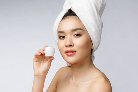 健康和美容的概念有吸引力的亚洲妇女在她的皮肤上涂霜, 在白色隔离