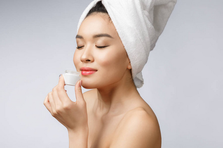 健康和美容的概念有吸引力的亚洲妇女在她的皮肤上涂霜, 在白色隔离