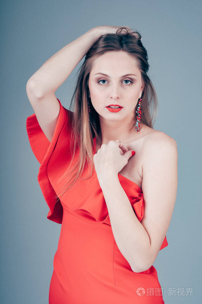 美丽的年轻白种人女士穿着红色的裙子在工作室摆姿势