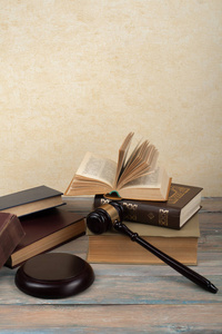 法律概念开放的法律书籍，木制法官木槌在法庭或执法办公室的蓝色背景。 文本复制空间