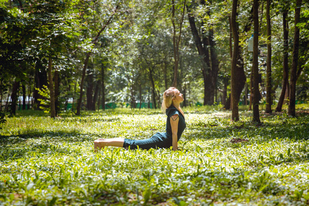 乌尔德瓦穆卡斯瓦纳萨纳。 瑜伽体式在自然界。 每天瑜伽姿势。 练习年轻女人。 公园里的瑜伽