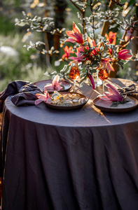 美丽的桌子设置在花园的日落光。 玉兰树下的玉兰花装饰的桌子