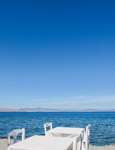 白色的餐厅桌在海滩上的夏季旅行，假期和夏季的概念.提供海景的完美午餐
