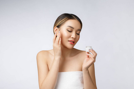 亚洲妇女在皮肤应用化妆品奶油在查出的白色背景