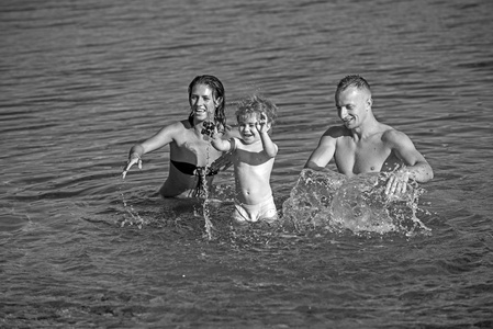 爱和信任作为家庭价值。快乐家庭在日落时的海水中嬉戏的爱
