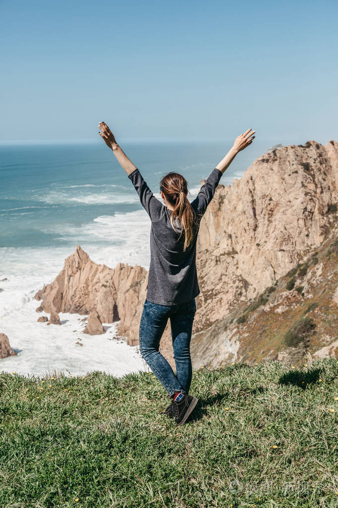葡萄牙大西洋旁边的女孩举起双手, 显示出她是多么高兴