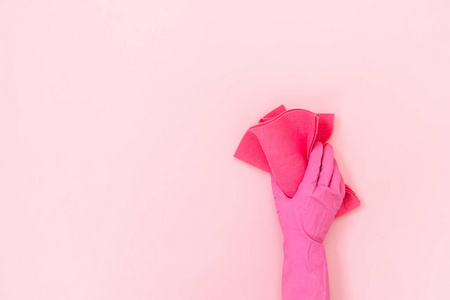 女人戴着橡胶手套，手里拿着清洁毛巾，孤立在粉彩背景上，空着文字空间