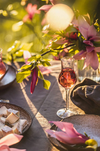 美丽的桌子设置在花园的日落灯光下。在木兰树下装饰着玉兰花的桌子