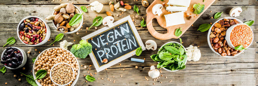 健康植物纯素食品素食蛋白来源豆腐纯素牛奶豆类坚果豆浆菠菜和种子。 旧的木制背景复制横幅