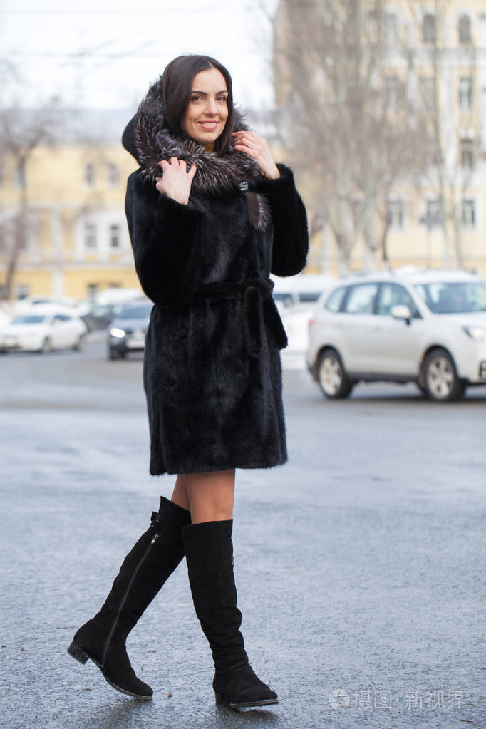 全身都是年轻漂亮的黑发女人穿着毛皮貂皮大衣在冬季公园摆姿势模特穿