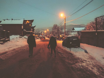 冬天的晚上。孩子们在雪地里散步。在一个下雪的夜晚的小屋。巴库里亚尼山区滑雪胜地