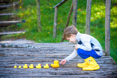可爱的孩子在公园里玩橡胶鸭子在古老的木制乡村桥上玩得很开心。 童年快乐放松冒险友谊的概念。 阳光明媚的秋日在森林公园。