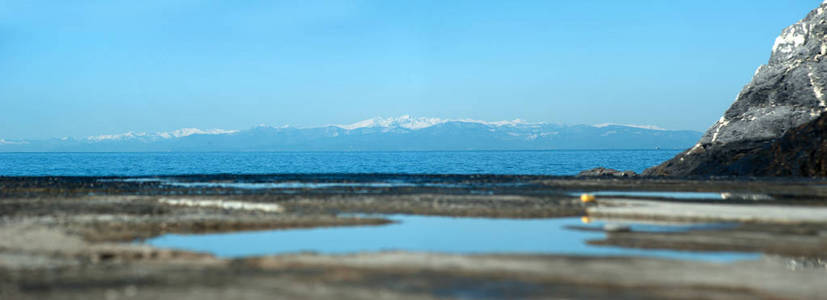 在码头和雪山背景的水中反射的蓝天