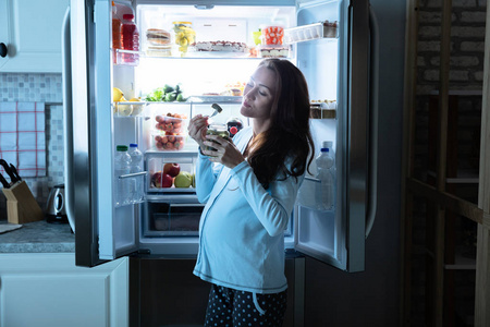 孕妇在开放式冰箱前吃泡菜图片