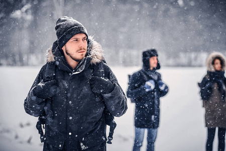 一个年轻的徒步青年, 背着背包和他的朋友们一起在冬林里散步