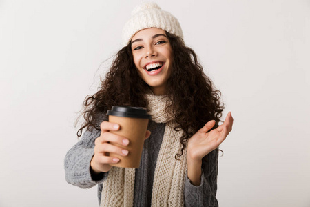 穿着冬巾的年轻女子站在白色背景下，手里拿着一杯咖啡