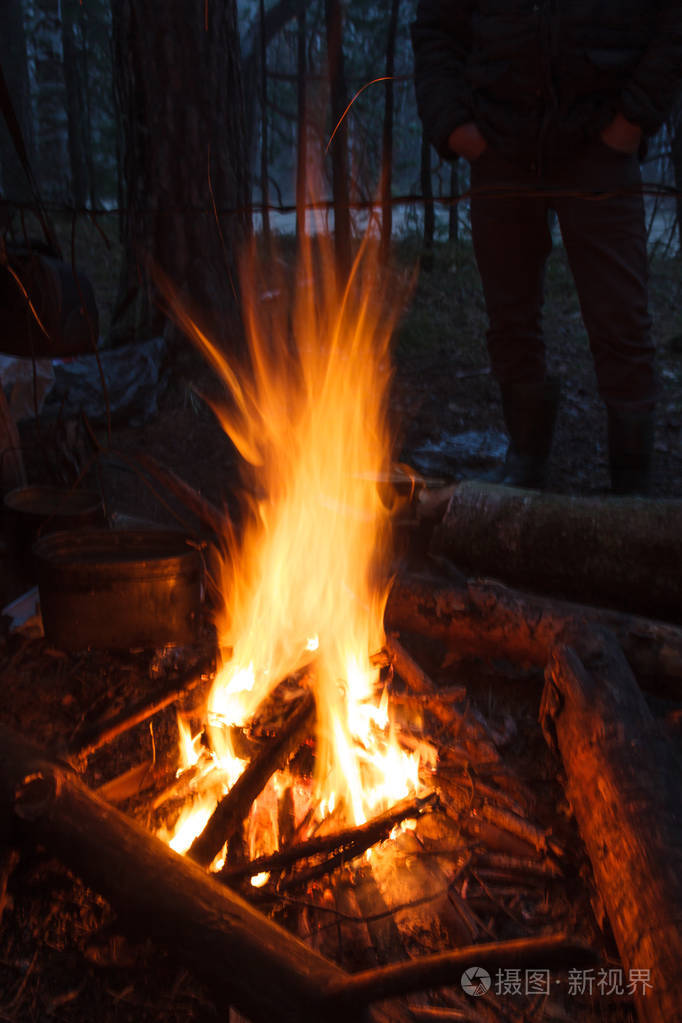 森林中夏季傍晚的明亮篝火和背景中游客的剪影