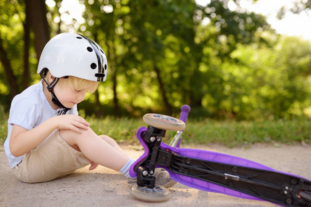 戴安全帽的幼儿学骑滑板车。活动户外游戏中幼儿碰撞