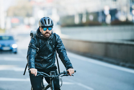一个前视图的男性自行车快递在城市运送包裹。复制空间