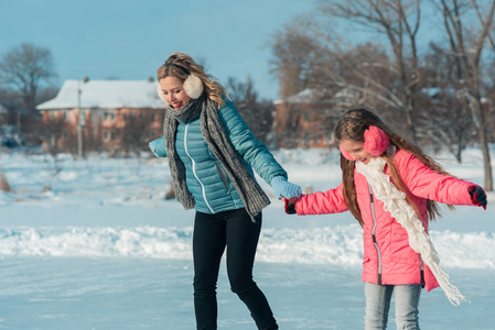 年轻的家庭在雪公园的冰区玩耍