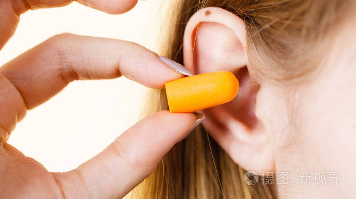 女人把耳塞塞进耳朵在响亮的地方消除噪音