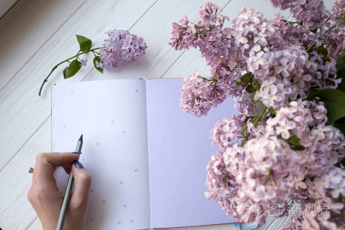白色桌面上的丁香和记事本女人在笔记本上写字上面的风景