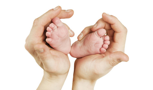 闭上母亲的手，握住新生婴儿的脚，呈听觉形状。 可爱的小男孩脚趾宏观照片与毛绒衬里舒适的毛毯背景