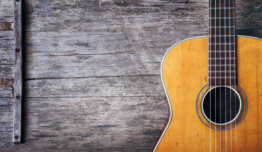 特写旧的声学西班牙吉他在乡村木制背景从上面。 流行音乐曲调和歌曲设计横幅。 上面的风景。