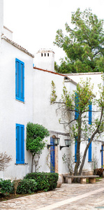 阳光明媚的夏日，在古希腊城市的街道上，白色的房子，蓝色的百叶窗和瓷砖屋顶