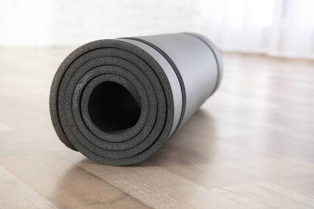 室内地板上滚动的灰色瑜伽垫