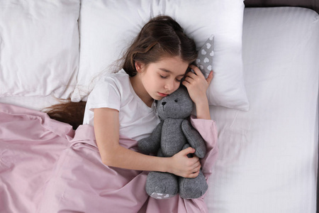 美丽的小女孩，带着玩具兔子睡在俯视图